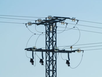 Low angle view of electricity pylon against clear sky