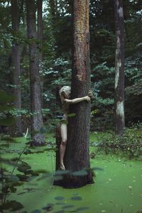 Bare lady hugging large tree in marsh scenic photography