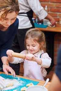 Daughter preparing food with mother on table