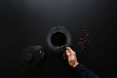 Midsection of man holding lighting equipment against black background