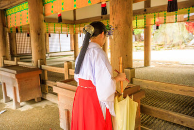 Rear view of woman standing at temple against building