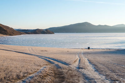 Scenic view of beach in winter against clear sky