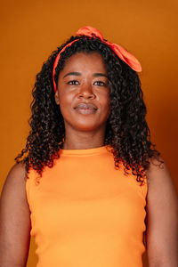 Portrait of young woman against yellow background