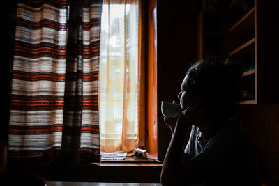 Side view portrait of a young woman sitting at home