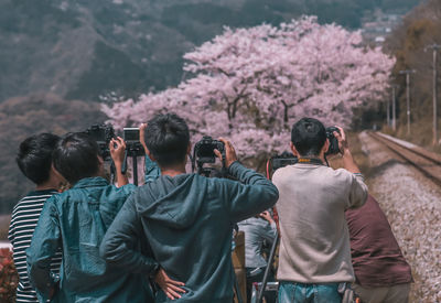 Rear view of people standing against trees