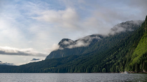 Scenic view of sea by mountains against sky