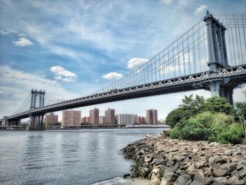 Low angle view of suspension bridge against cloudy sky