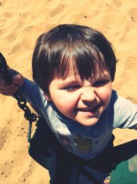 High angle view of happy boy sitting on swing