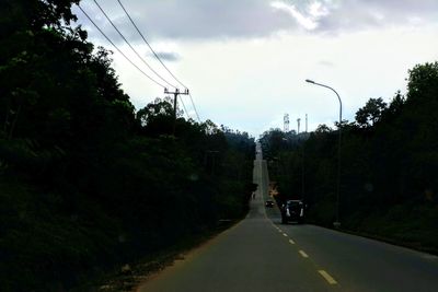 Road amidst trees against sky