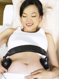 Pregnant woman with headphones on stomach