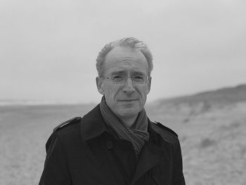 Portrait of man standing at beach against sky