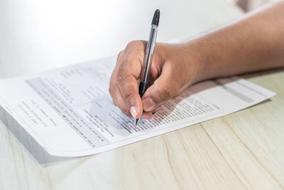 Close-up of hand holding book on table