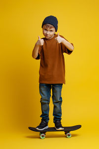 Portrait of boy standing against yellow background