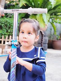 Side view of girl looking away while standing by push scooter