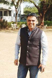 Smiling mature man wearing coat standing on field