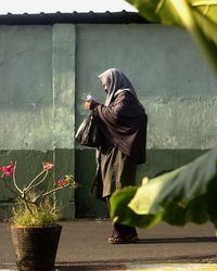 Side view of a woman walking against built structure