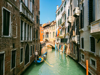 Gondola moored on canal amidst buildings