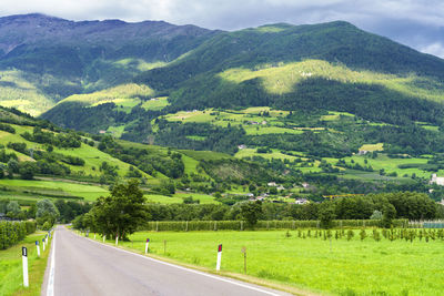 Scenic view of green landscape and mountains against sky