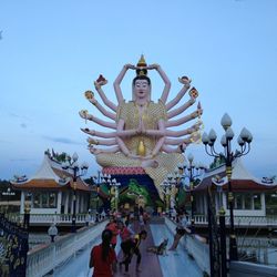 People in front of temple against clear blue sky