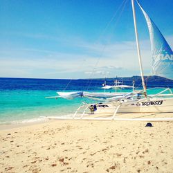 Outrigger boat on beach against cloudy sky