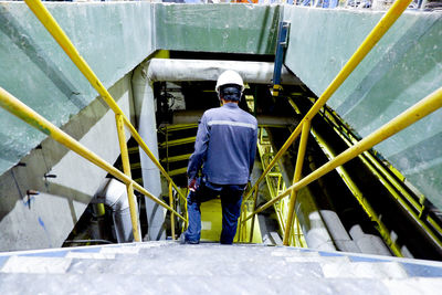 Rear view of man standing on railing