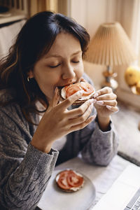 High angle view of woman eating healthy sandwich in breakfast at home
