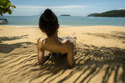 Rear view of man sitting on beach