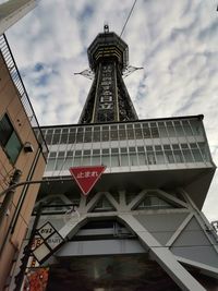 Low angle view of communications tower against cloudy sky