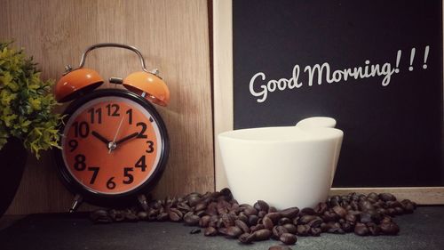 Close-up of alarm clock and coffee beans on table