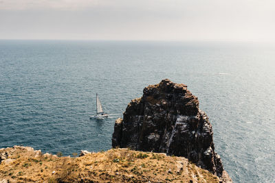 Sailing boat at cap frehel cliffs, brittany, france. atlantic ocean french coast