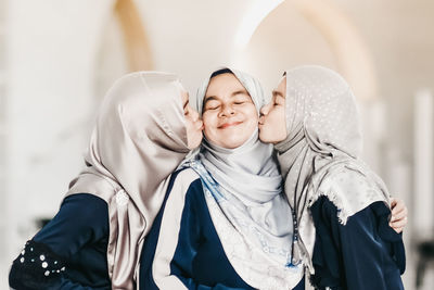 Friends kissing young woman