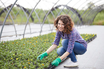 Portrait of smiling young woman working in greenhouse