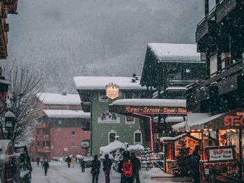 People on street amidst buildings in city during winter