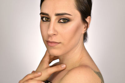 Close-up portrait of shirtless woman against white background