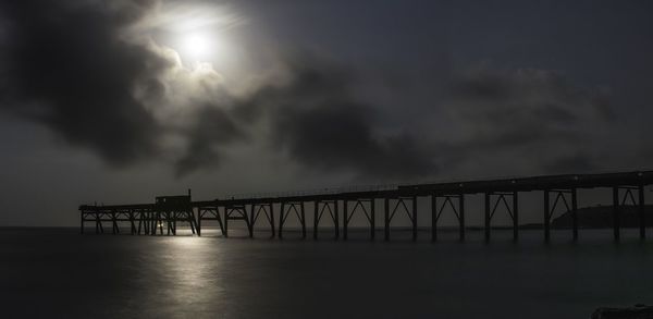 Pier on sea against cloudy sky