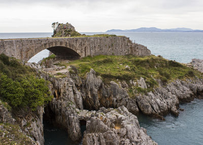 Arch bridge over sea against sky