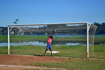 Full length of man playing on field against clear sky