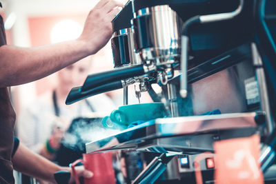 Midsection of man dispensing coffee from machine at cafe