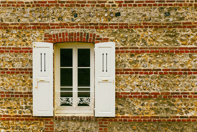 White window with white shutters on brick facade, etretat-normandy