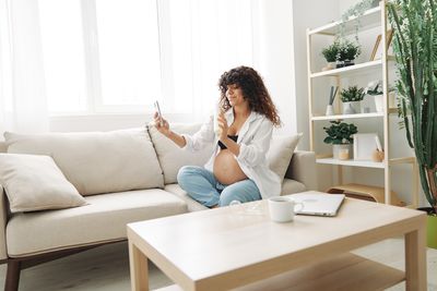 Young woman using laptop while sitting on sofa at home