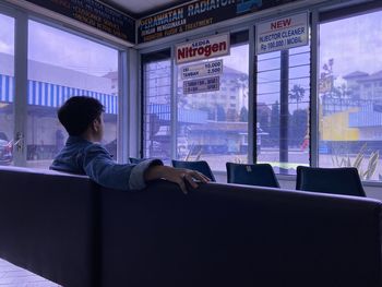 Side view of woman looking through window