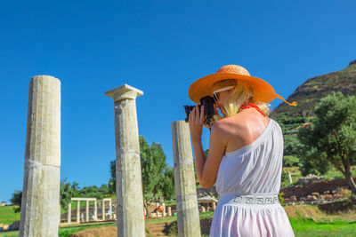 Woman wearing hat standing against blue sky