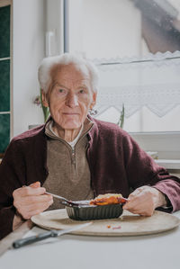 Portrait of woman holding food while sitting on table