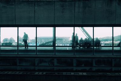 Silhouette man walking on railroad station platform seen through window