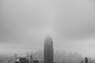 Empire state building against sky in city during winter