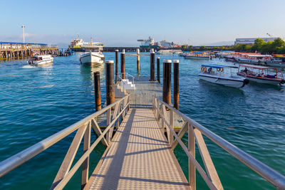 Boats moored at harbor in city against clear sky