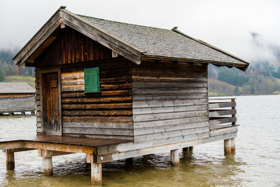 Hut by spitzingsee lake  against gray sky