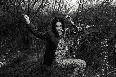 Portrait of woman standing by tree in forest