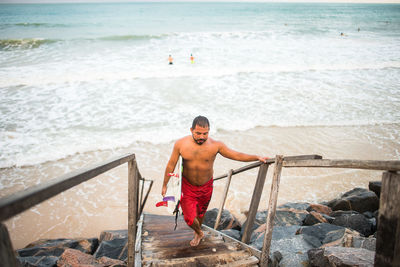 Full length of shirtless man at beach