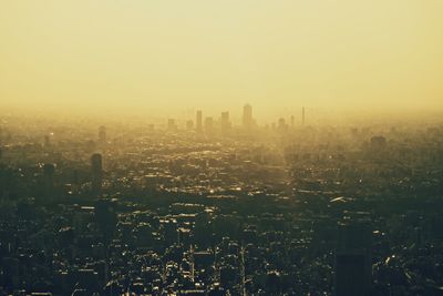 Aerial view of buildings in city against sky during foggy weather